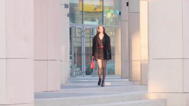 Fashion girl walking towards the camera between building columns