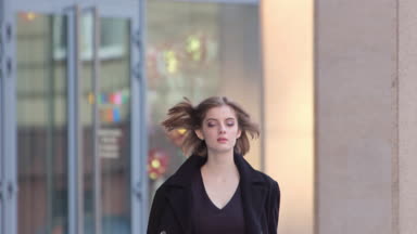 Attractive fashion girl in black walking towards the camera