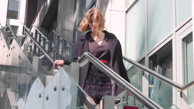 Fashion girl in black clothing with red bag goes down the stairs