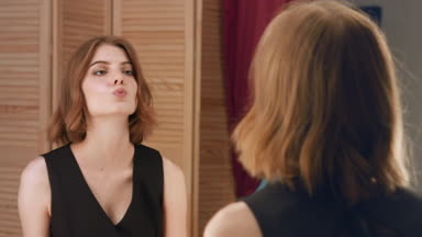 Young attractive woman make up her lips in front of the mirror
