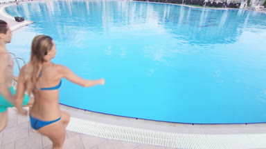 Cheerful couple jump in swimming pool