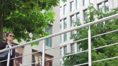Business woman walking along the hand rail against the office building