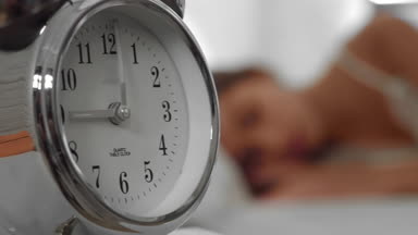 Young woman waking up in the morning by the alarm clock