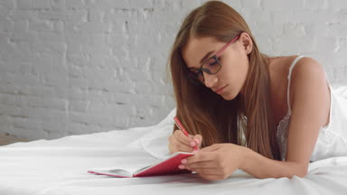 Designer lying in bed at home, develops a design and draws sketches