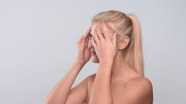 Young woman touching her face, looking at the camera and smiling