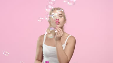 Portrait of Young woman blowing soap bubbles and smiling.