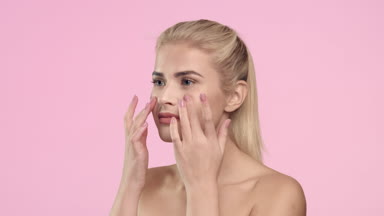 Blonde woman touching her face, looking at the camera and smile.