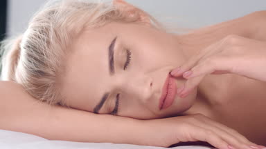 Blonde woman touch her smooth skin with closed eyes