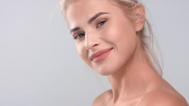 Woman puts her chin on her shoulder and looks at the camera