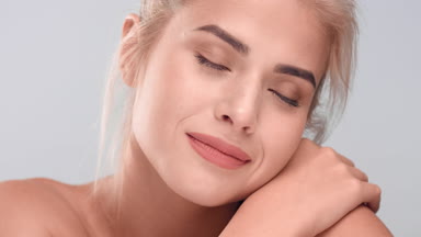 Woman softly touches her healthy skin and looks at the camera