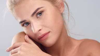 Woman strokes her shoulders, chin, neck and looks at the camera