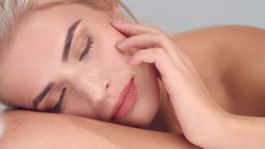 Girl raises her head looks at camera and softly touches her skin