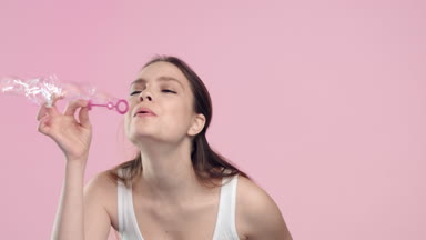 Young woman blowing bubbles and turns to the camera