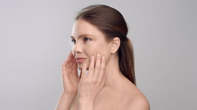 Young woman turning to the camera touching her face and smile