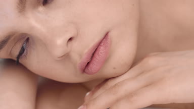Young brunette woman strokes her face skin and looking at camera