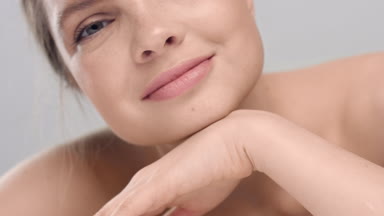 Woman raises her head, strokes her face and looks at the camera