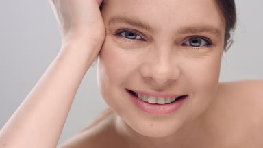 Woman looking at camera, touching her face skin and smiling