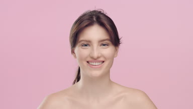 Young pretty woman with smooth skin looks at camera and smiling