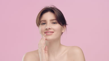 Young pretty woman strokes her smooth face skin with pleasure