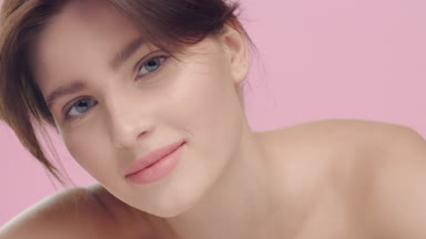Pretty woman lays down head on hand, looks at camera and smiles