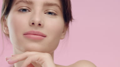 Young brunette woman with smooth healthy skin looks at camera