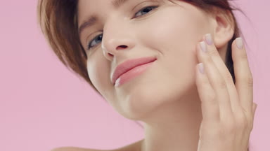 Young woman with smooth healthy skin gently touches her face