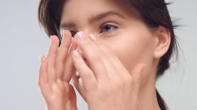 Young woman with healthy smooth skin gently stroking her face
