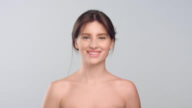 Woman with smooth skin standing in front of camera and smiling