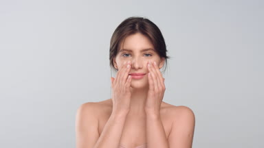 Woman with smooth healthy skin strocks her face and smiles