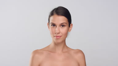 Woman with perfect skin turns and looks at the camera and smiles