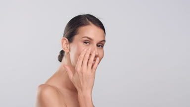 Young slim woman touches her smooth face skin and smiles