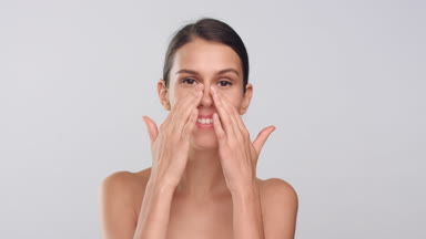 Young slim woman touches her smooth face skin and smiles