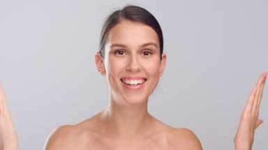 Young woman opens and shut her eyes with hands and smiles