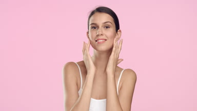 Young woman in white t-shirt touches her face and smiles