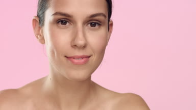 Young woman with soft skin applies moisturizing cream on face