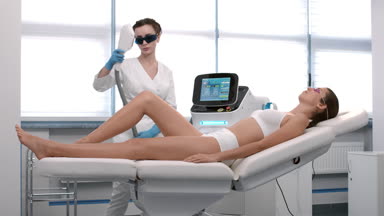 Beautician perform laser hair removal procedure on patient's leg