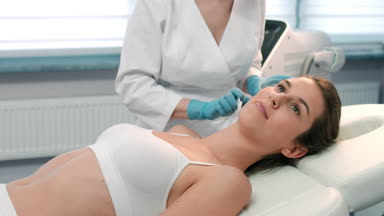 Cosmetologist applies electrode gel on the patient's face