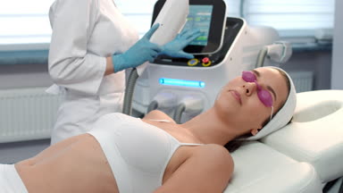 Cosmetologist performs laser treatment procedure.