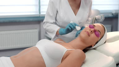 Cosmetologist applies electrode gel on the patient's face