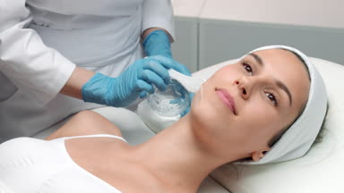 Doctor-cosmetologist applying ipl gel on patient's face