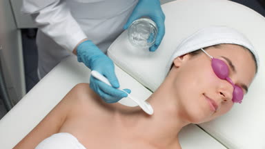 Cosmetologist applies electrode gel on the patient's neck
