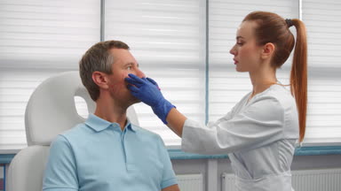 Beautician drawing correction lines on male patient's face