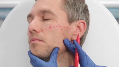 Close-up shot of drawing correction lines on man's face