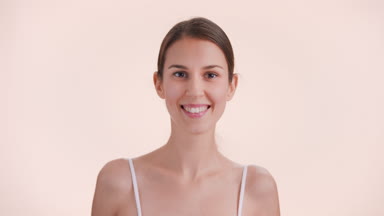 Woman lifts up her chin, looks at the camera and smiles widely