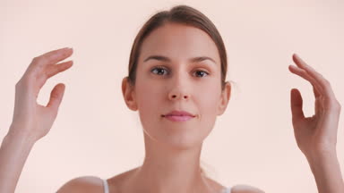 Lady lifts up her chin and looks at camera toching her face skin
