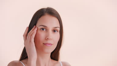 Lady touches her face sliding fingers from cheekbone to the chin