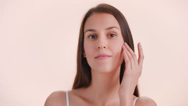 Young woman softly touches face running fingers along her cheek