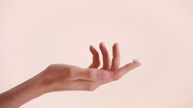 Female hand with a drop of a beauty cream on the tip of a finger