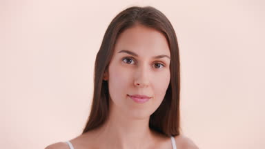 Young woman makes a beauty cream smear on her face and smiles