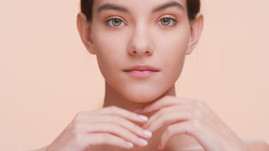 Young woman strokes her face skin, looks at the camera and smile